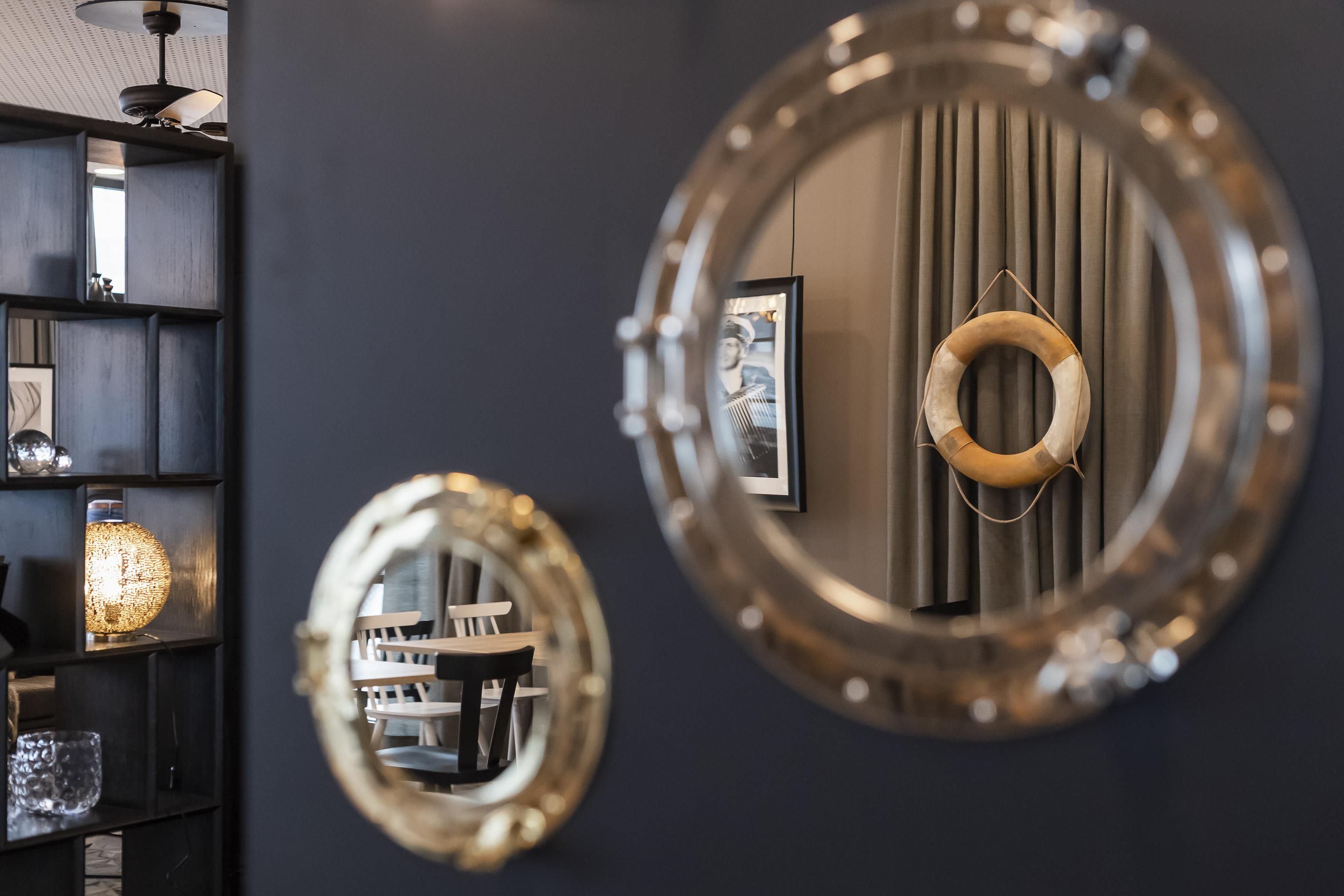 A room with a circular mirror, a framed picture, and a decorative ring on the wall.