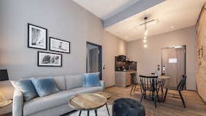 Ein modernes Wohnzimmer mit einer Couch, einem Couchtisch, einem Hocker und einem Essbereich mit Stühlen und einem Tisch.