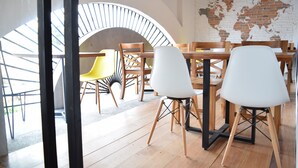 Un comedor moderno con mesas y sillas de madera, una silla amarilla y un mapa del mundo en la pared.