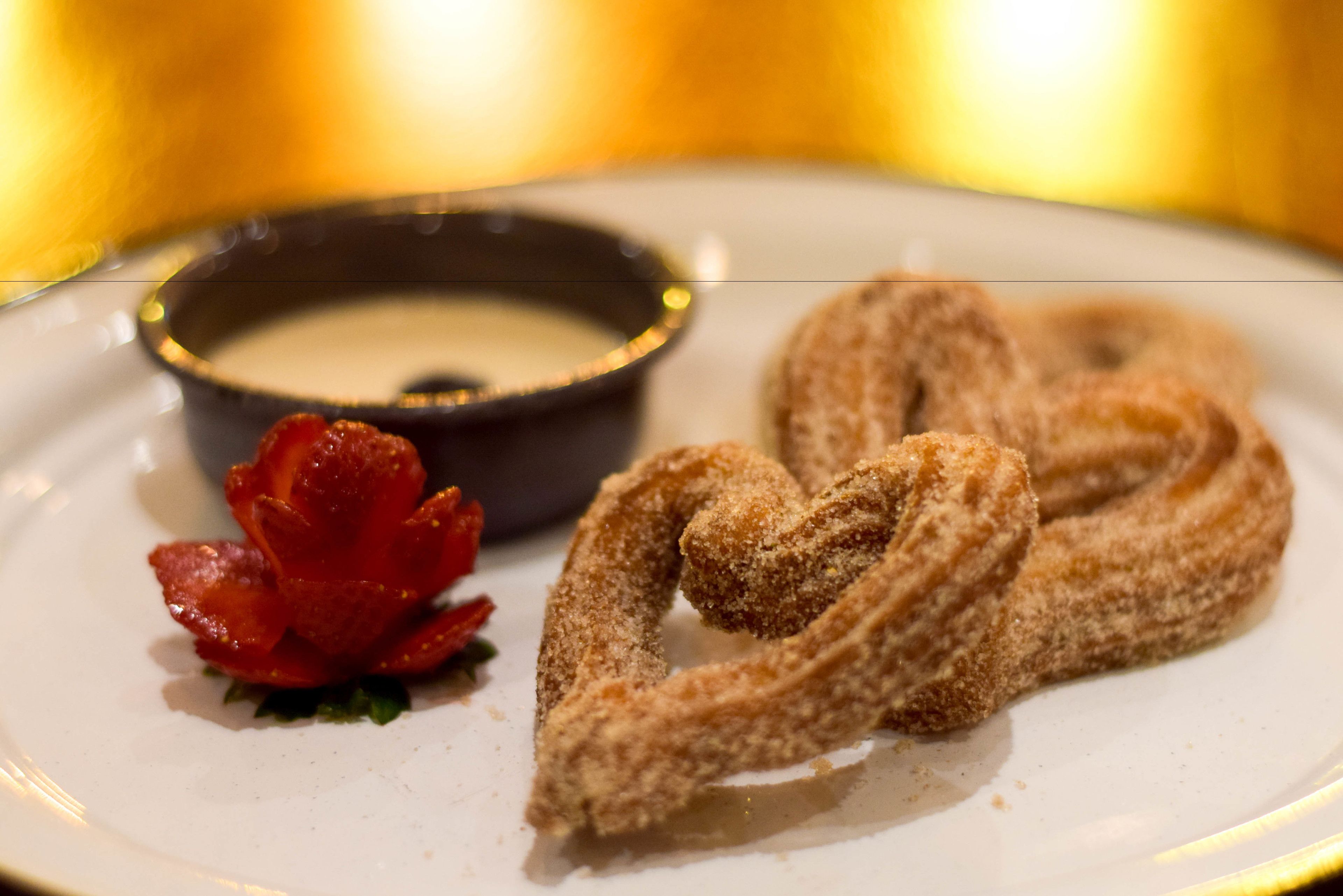 A plate with churros and a small bowl of sauce.