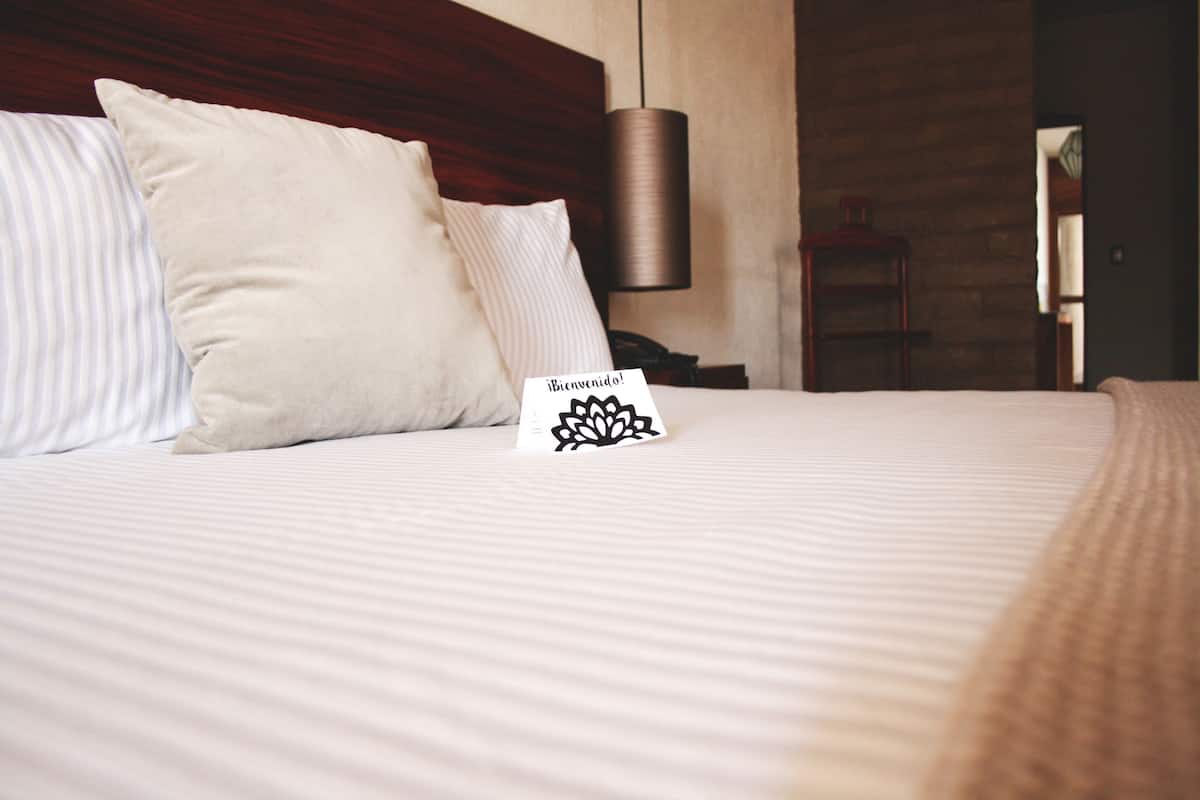 A neatly made bed with striped bedding and a welcome card.