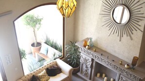Una sala de estar con sofá, sillón, mesa de centro y chimenea decorada con objetos decorativos.