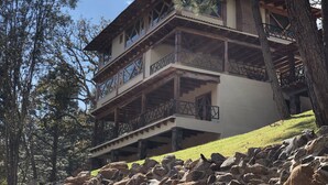 Un edificio de varios pisos con balcones, rodeado de árboles y rocas.