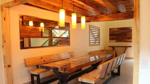 Una mesa de madera para comer con bancos, techo de madera y lámparas colgantes.