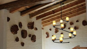 Techo con vigas de madera a la vista y una araña con múltiples lámparas.