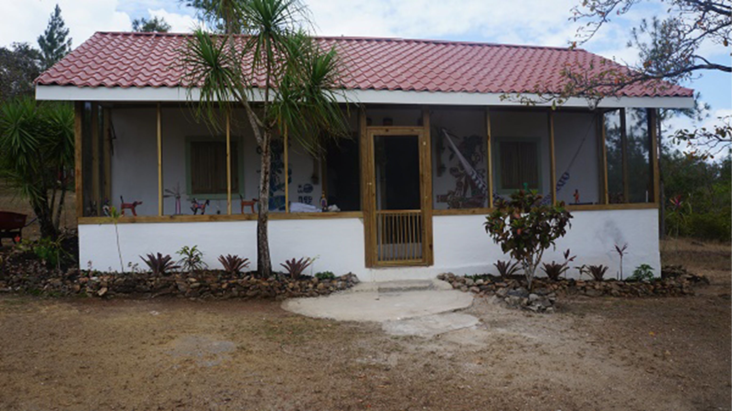 A single-story building with a red-tiled roof, a wooden door, and a covered porch area.