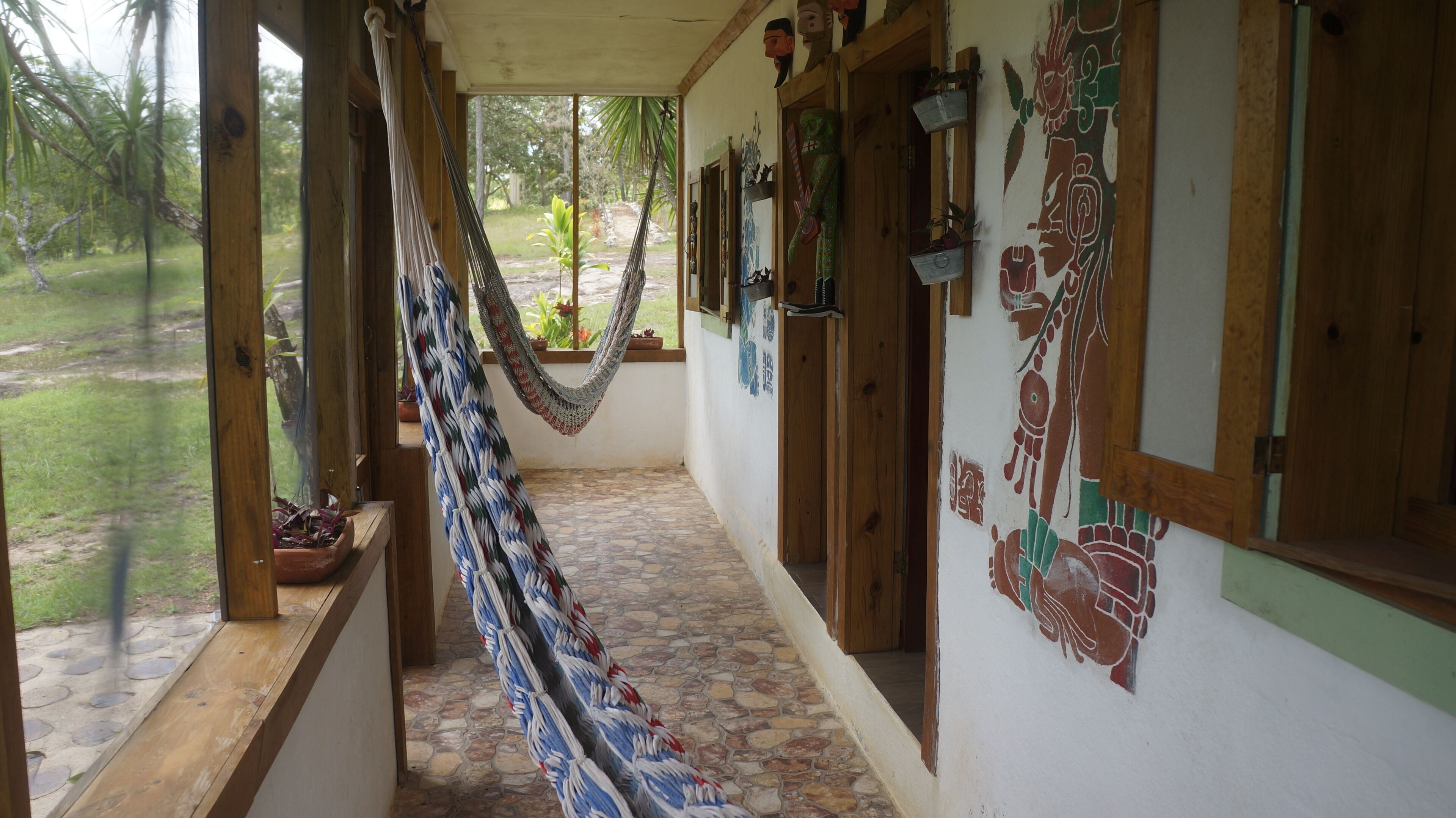 A corridor with a hammock, wooden doors, and a mural.