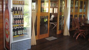 A room with a frosted glass door, wooden furniture, and a beverage vending machine stocked with various beers. - Chez Paul Ambodiatafana (Ambodiatafana)