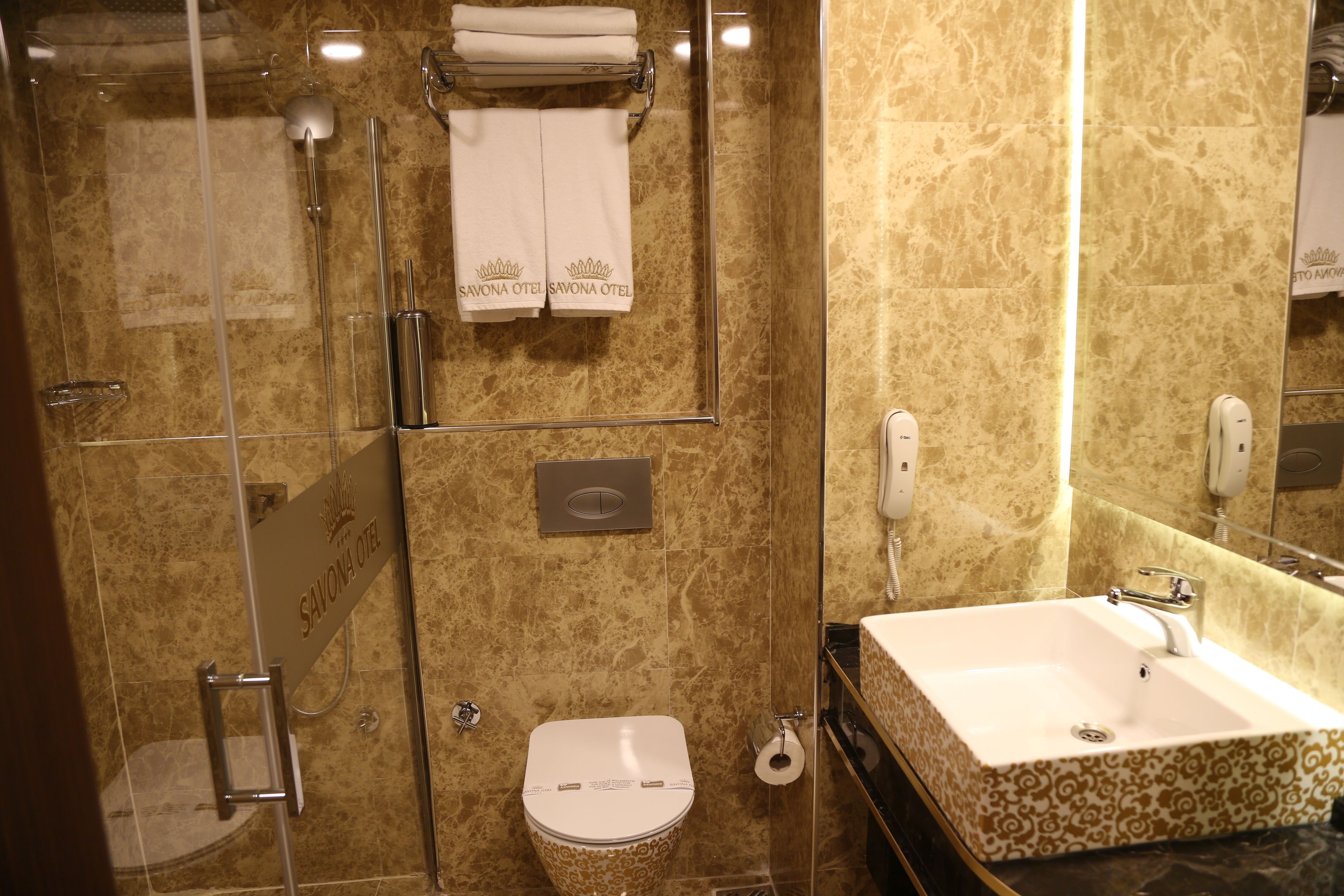 Une salle de bain dotée d’une douche à parois de verre, de toilettes et d’un lavabo avec un plan de travail à motifs.