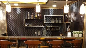Una zona de bar con taburetes altos, un sofá amarillo y un suelo de mármol.