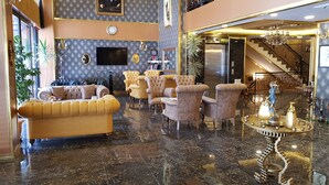 Un vestíbulo lujoso con asientos cómodos, una escalera imponente y una pieza decorativa central.