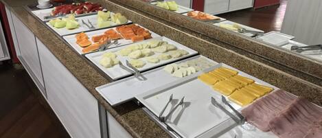 A buffet with various food items including fruits, cheeses, and meats.