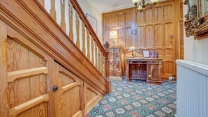 A wooden staircase with a patterned carpet, a desk with a lamp, and wooden paneling. - The Grove (Whitby)