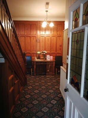 A wooden-paneled room with a desk, chairs, a chandelier, and a patterned carpet. - The Grove (Whitby)