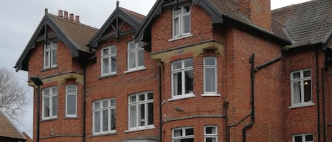 Un edificio de varios pisos de ladrillo con un letrero que indica que es una casa de huéspedes.