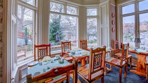 A dining area with a bay window overlooking a garden and a street view. - The Grove (Whitby)