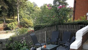 A patio with a table and chairs, surrounded by potted plants and a wooden fence. - The Grove (Whitby)
