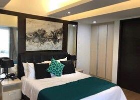 Un dormitorio moderno con una cama grande, una mesita de noche, una lámpara de escritorio, un cuadro en la pared y un armario.