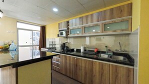 Cozinha moderna com armários de madeira, bancada preta e eletrodomésticos de aço inoxidável.