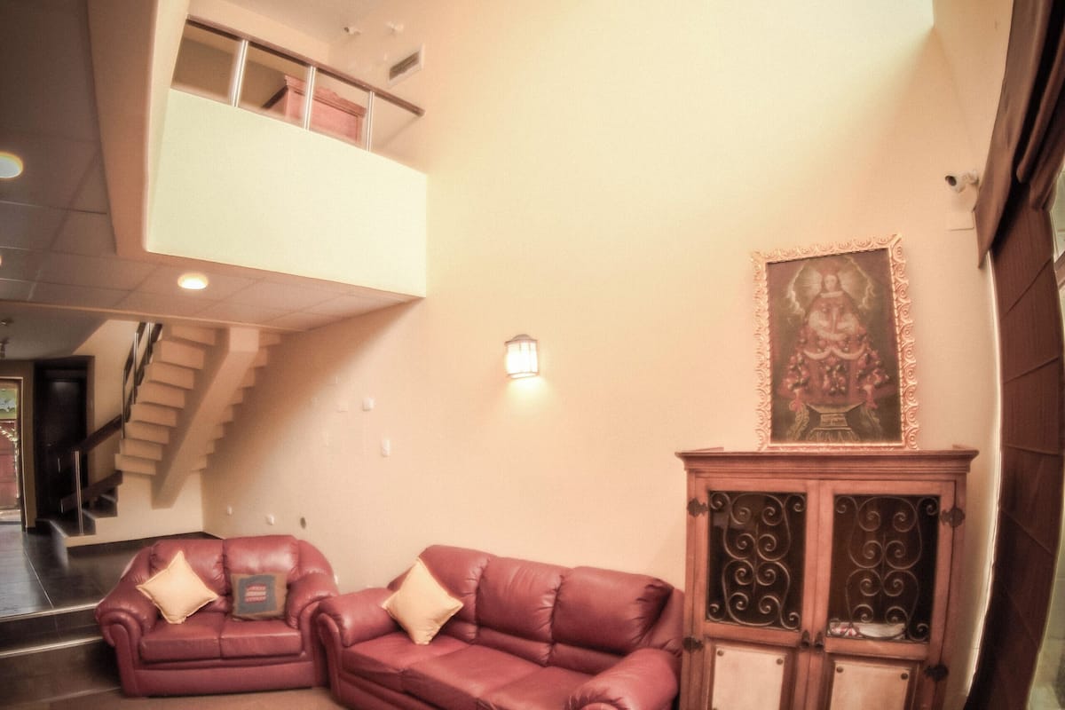 Uma sala de estar ampla com teto alto, uma escada que leva a um andar superior e um armário decorativo com uma moldura.