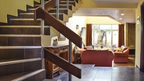 Escadaria que leva a uma sala de estar com lareira, sofá e mesa de centro.