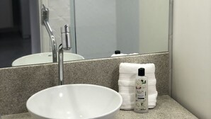 A bathroom with a white sink, a mirror, and a towel dispenser. - Ondina Apart Hotel (Salvador)