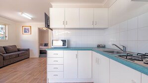 Una cocina compacta con armarios blancos, encimera verde azulado y estufa a gas integrada.