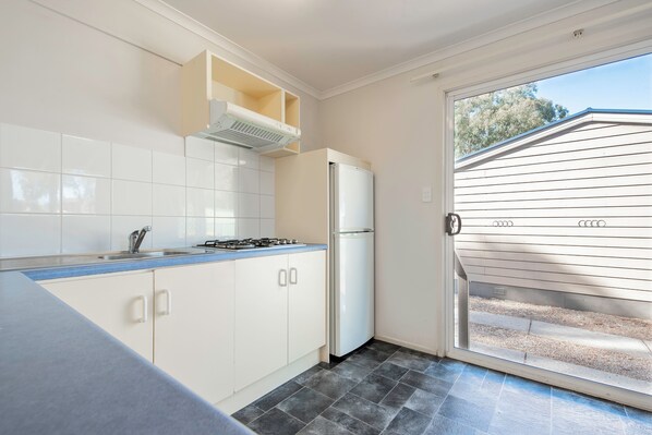 A kitchen with white cabinets, a gas stove, and a white refrigerator. - Echo Holiday Parks - Windsor Gardens (Windsor Gardens)