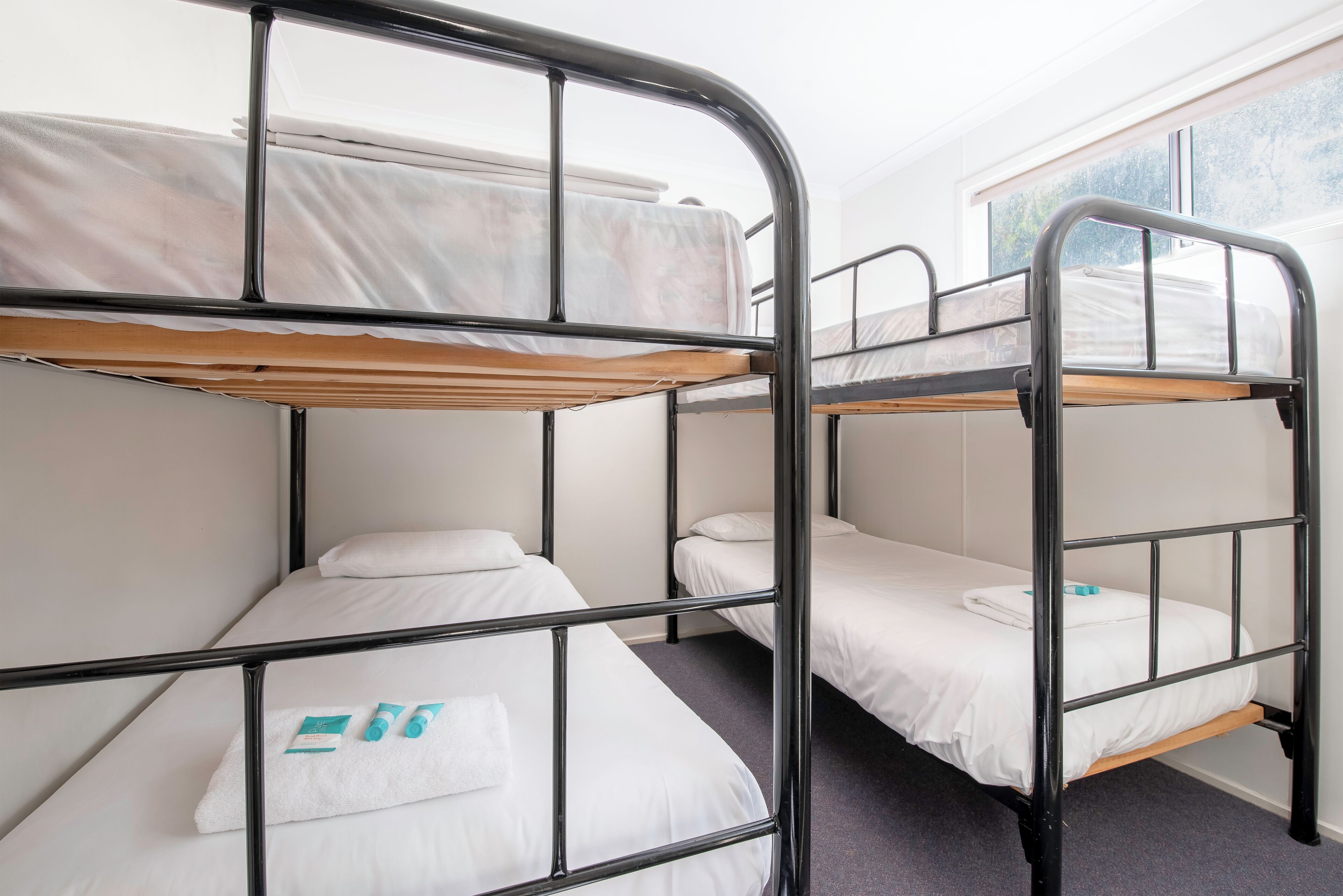 Une chambre de dortoir avec des lits superposés, une fenêtre et un sol recouvert de moquette.