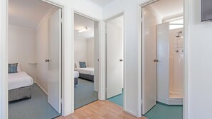 Una habitación de hotel con cama, mesita de noche y baño con ducha.