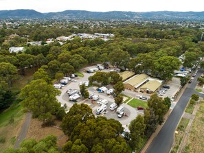An aerial view of a campground with RVs and tents, surrounded by dense trees and a road. - Echo Holiday Parks - Windsor Gardens (Windsor Gardens)