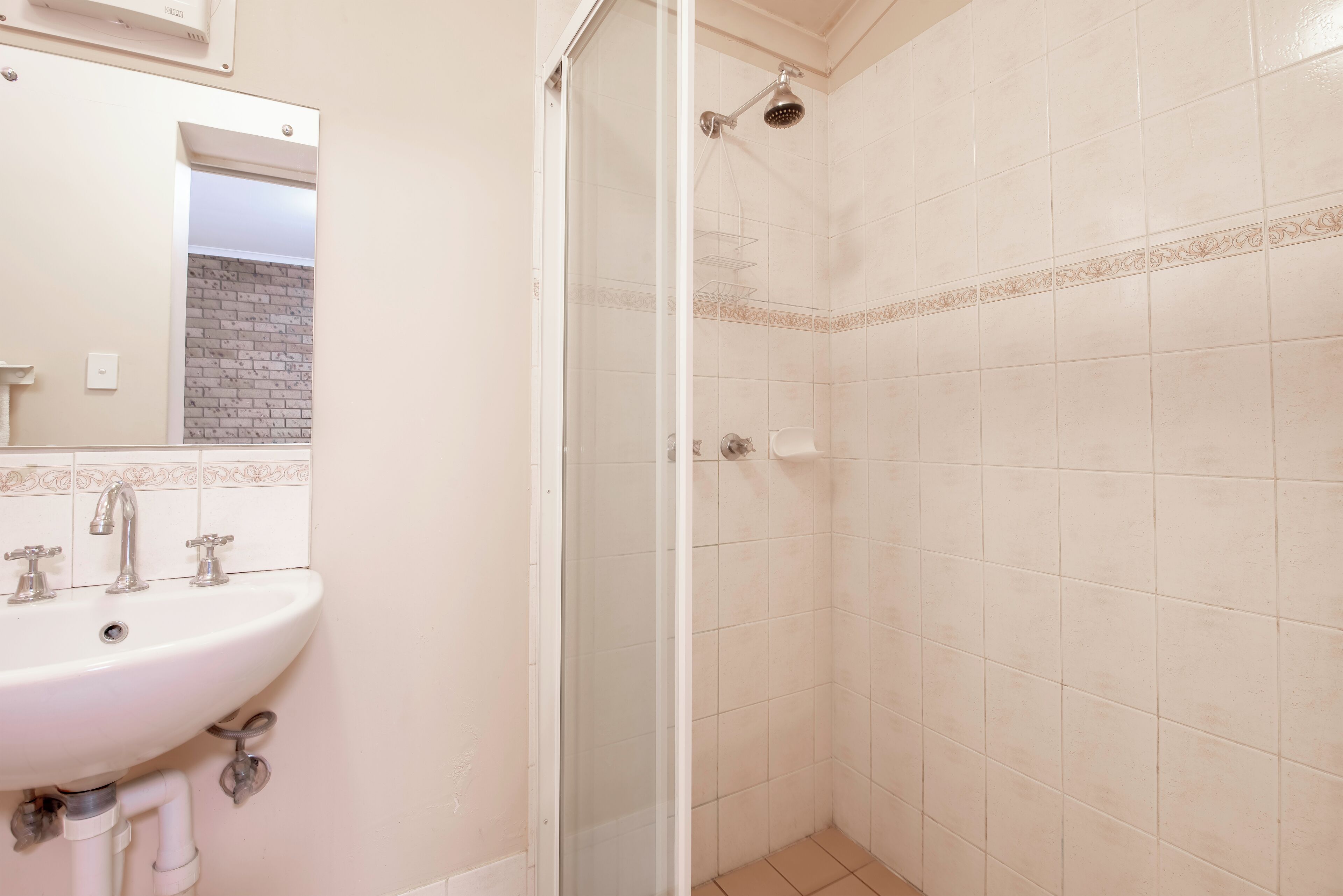 A bathroom with a white sink, a mirror, and a shower with a glass door.