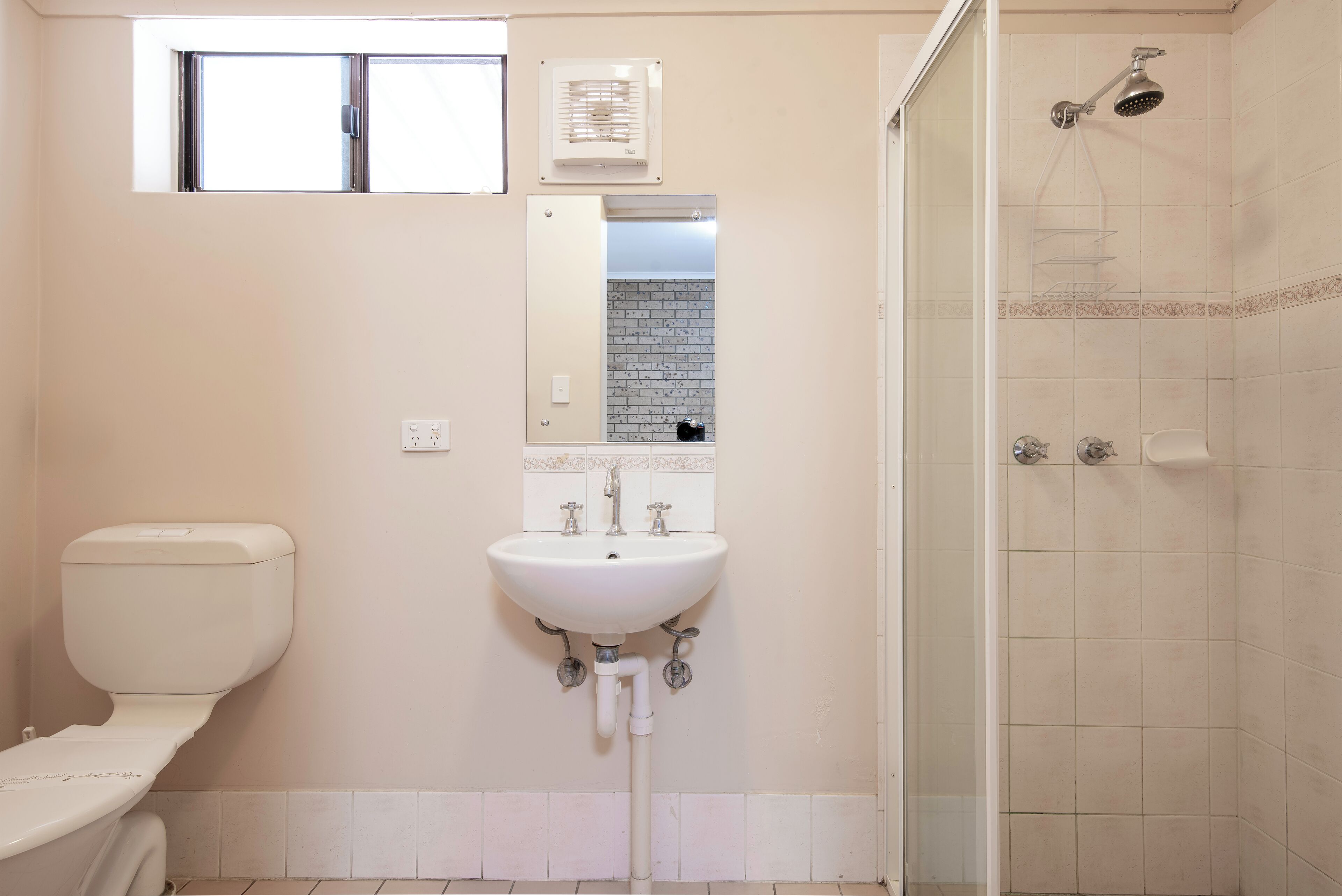 Un baño con inodoro, lavamanos, espejo y ducha.
