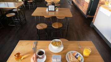 Ein Restaurant mit Holztischen und -stühlen, einer Bar und Blick auf die Straße.