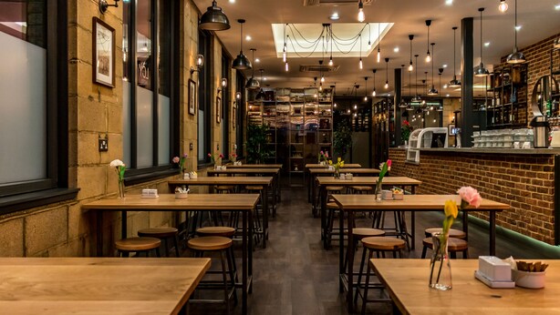 Ein Restaurant mit Holztischen und -stühlen, einer Ziegelwand und hängenden Lampen.
