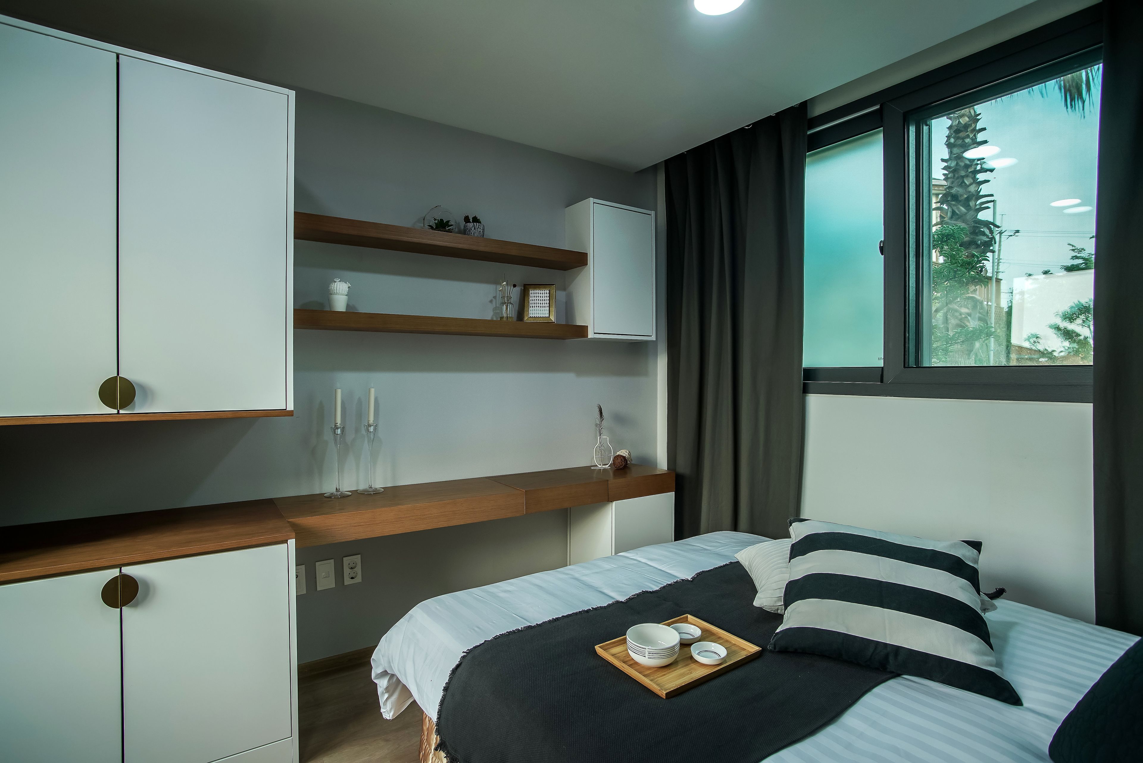 Une chambre à coucher moderne avec un lit, des tables de chevet et des étagères intégrées.