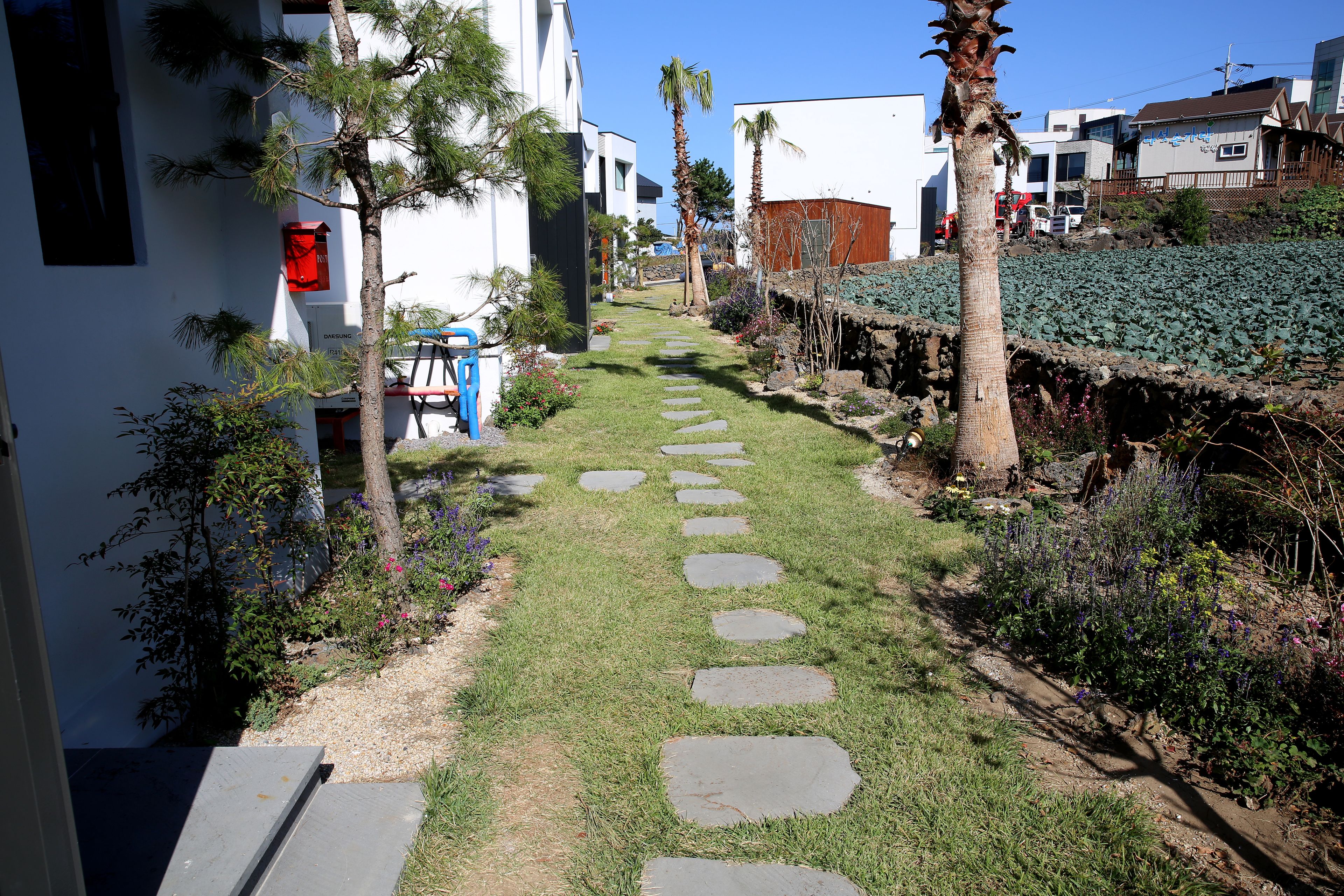Un sendero con losas de piedra que conduce a un edificio de fachada blanca y una silla azul en el exterior.