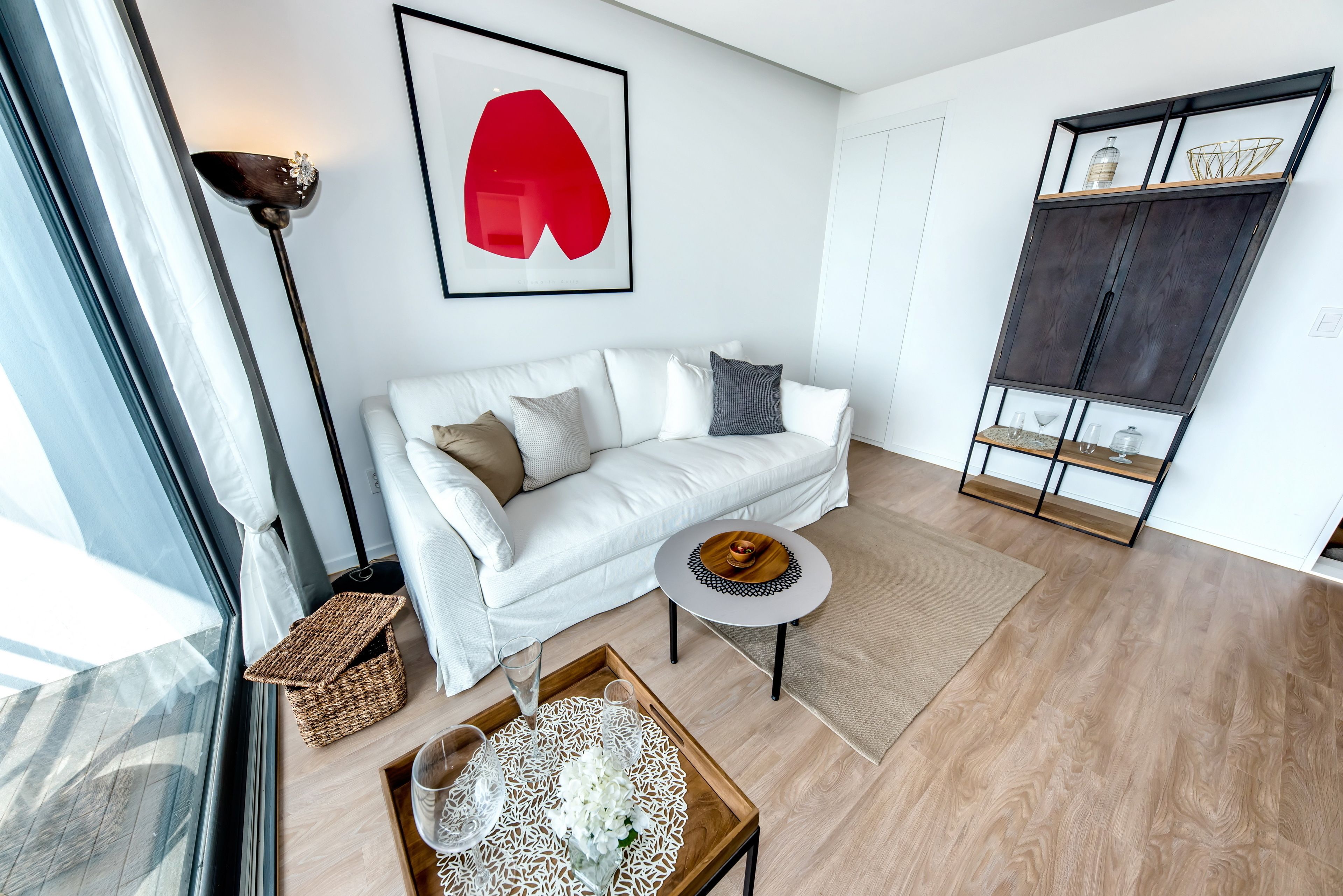 Uma sala de estar moderna com um sofá branco, uma mesa de centro redonda e um abajur.