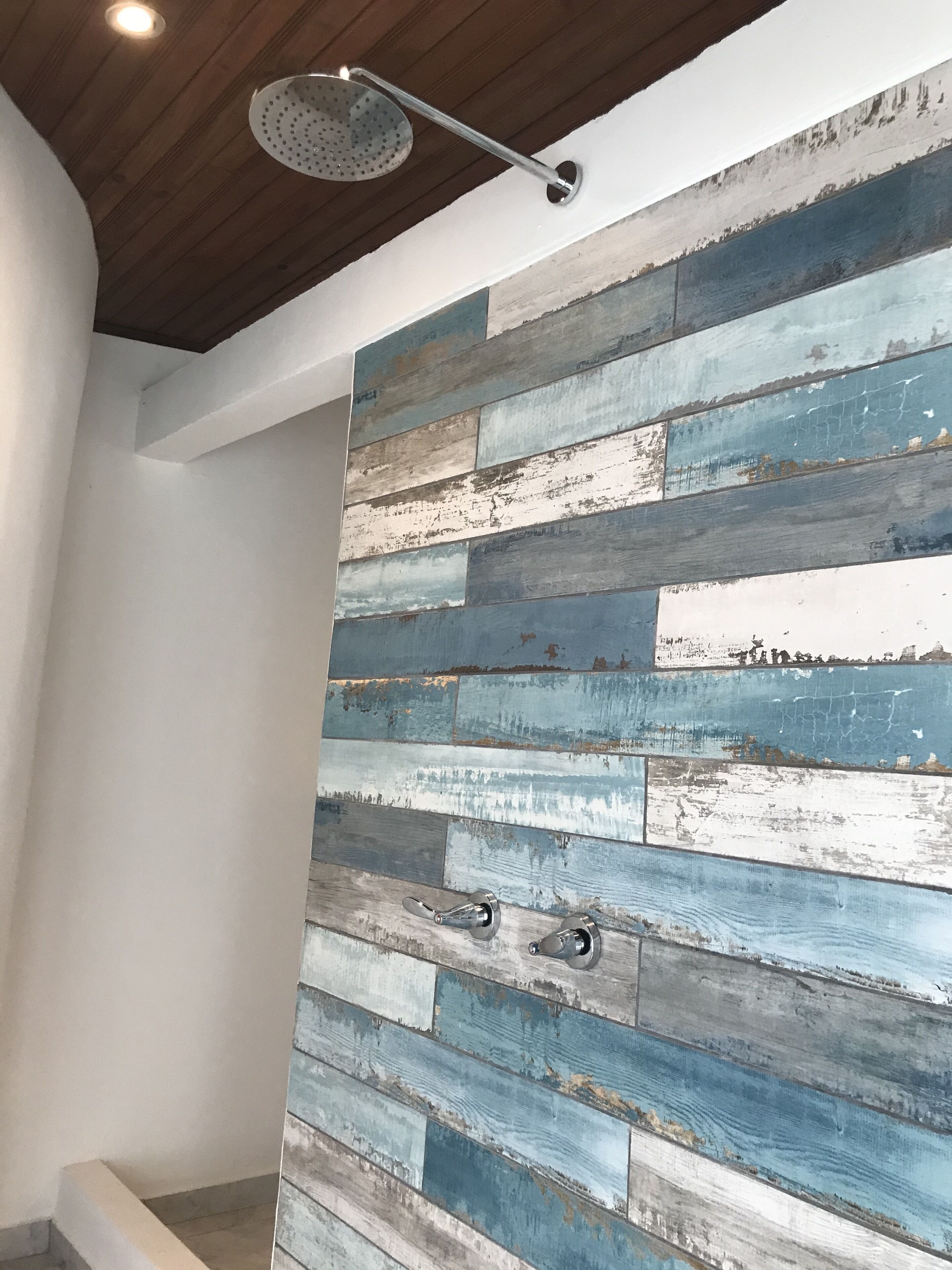 Una habitación con un panel de pared de madera rústica, un lámpara en el techo y una puerta con manija.