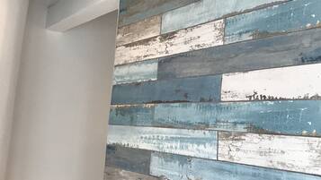 Una habitación con un panel de pared de madera rústica, un lámpara en el techo y una puerta con manija.