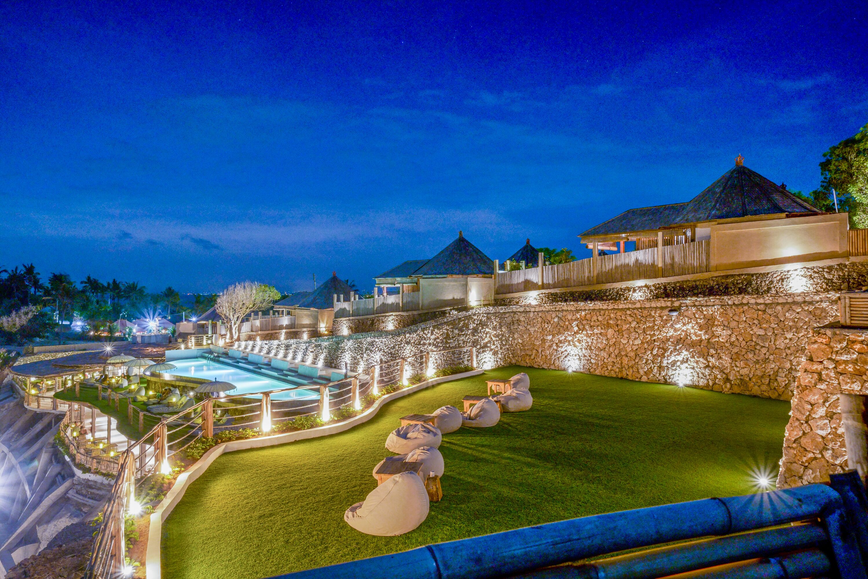Een resort met een zwembad, terras en een stenen muur.
