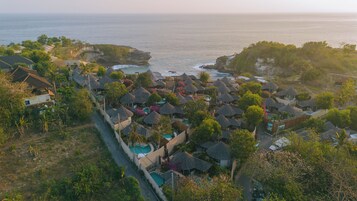 Vista aérea de un resort con varias cabañas, una piscina y vistas al océano.