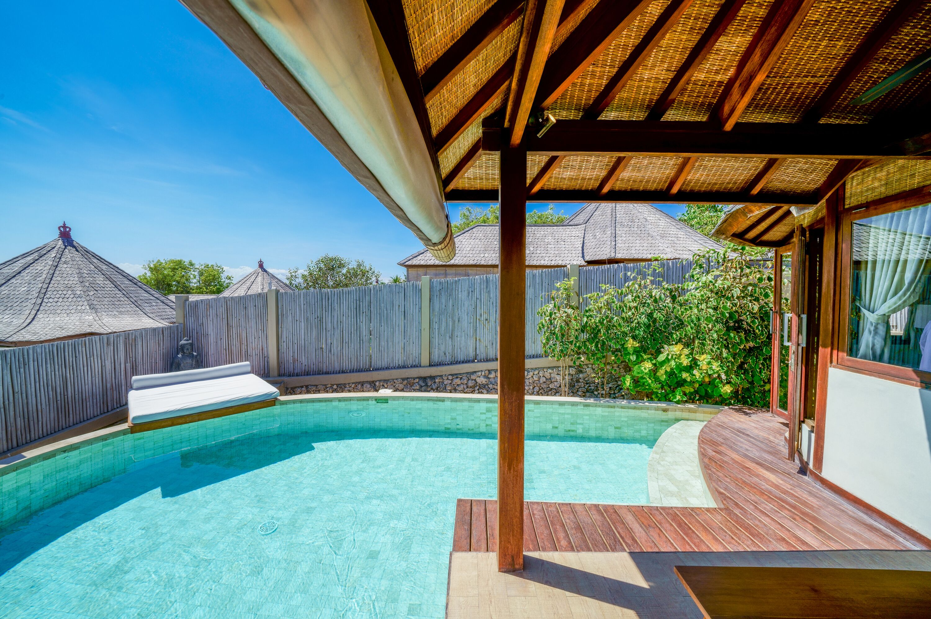 A swimming pool with a wooden deck and a covered area.