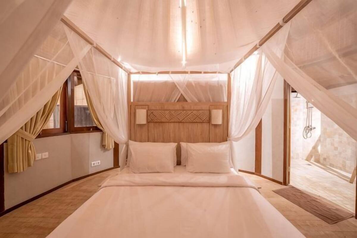Ein Schlafzimmer mit Himmelbett, Holz-Kopfteil und Blick auf eine Steinmauer.
