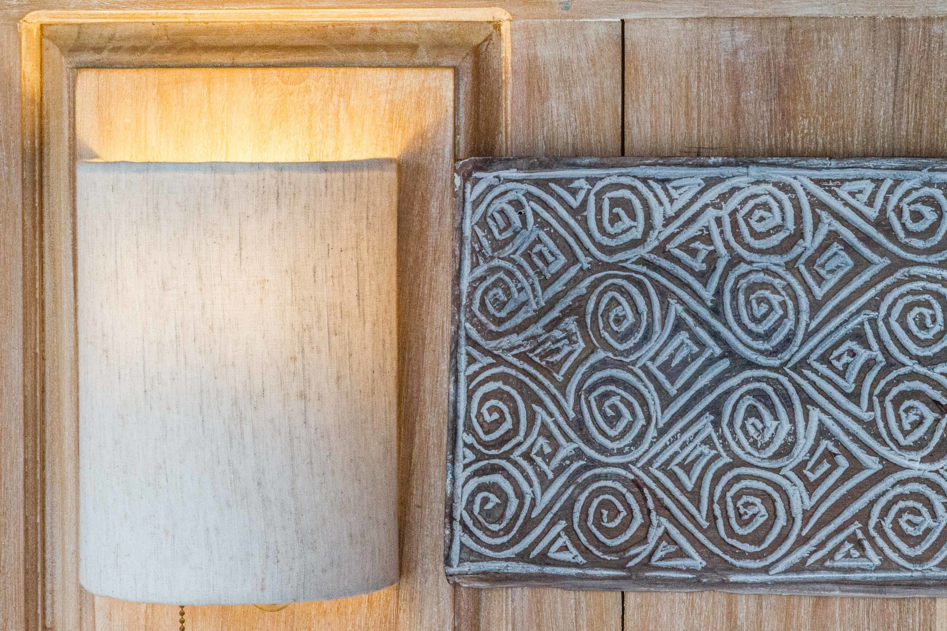 A wooden door with a simple, unadorned panel and a decorative metal plaque with geometric patterns.