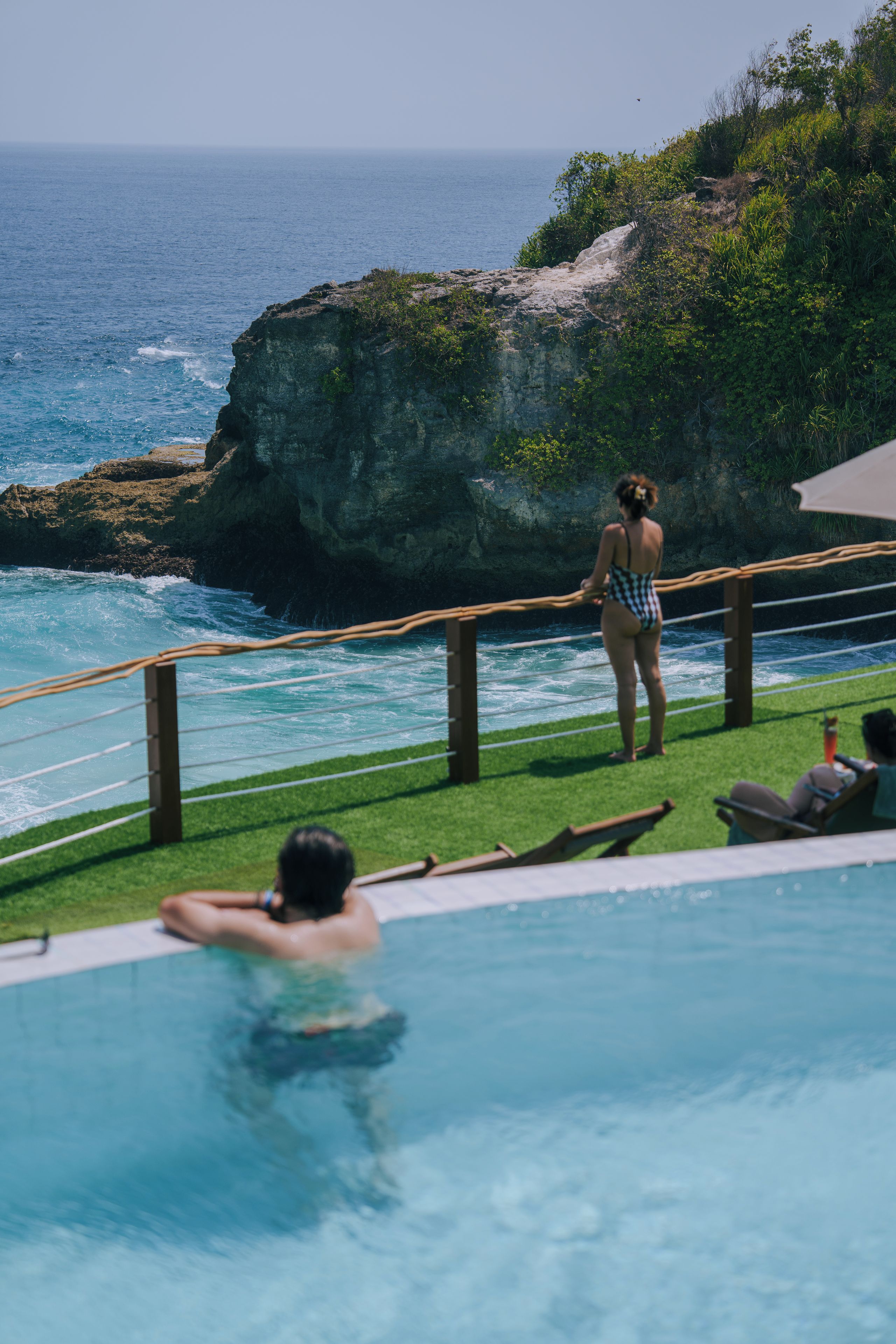 Zona de piscina con vista al océano y un acantilado rocoso.