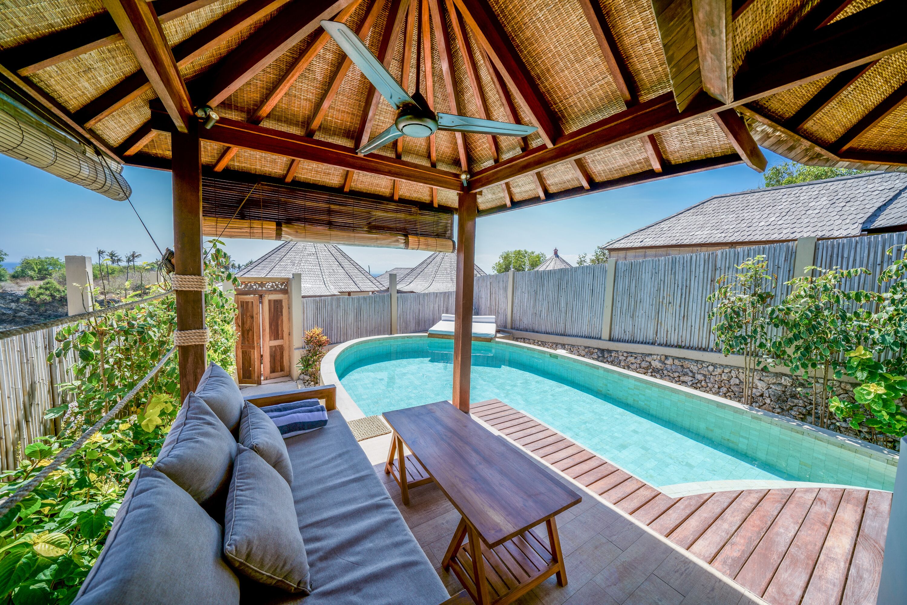 A covered outdoor area with a pool, wooden deck, and seating.