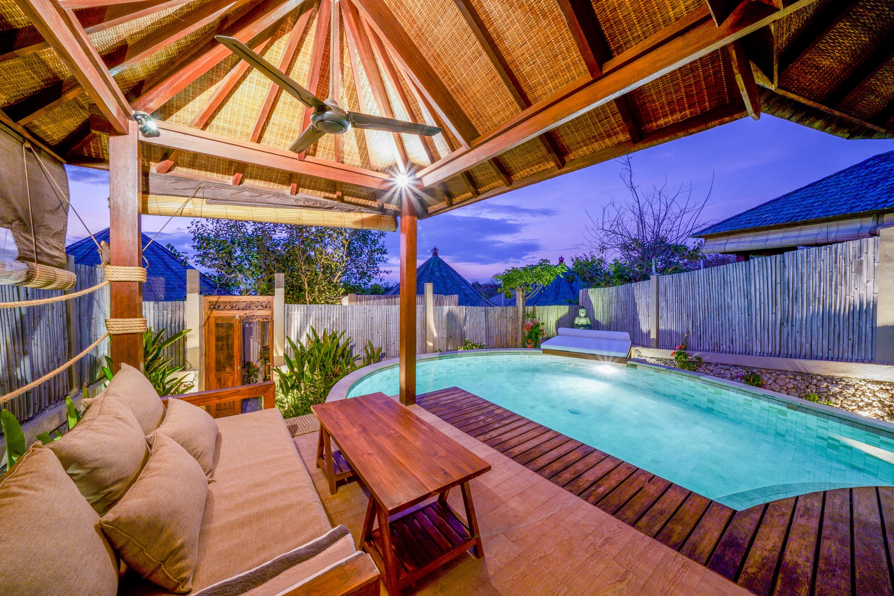 A wooden deck with a pool, a covered seating area, and a wooden fence in the background.