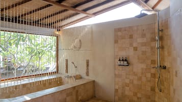 A bathroom with a shower, a bench, and a window with a view of greenery.