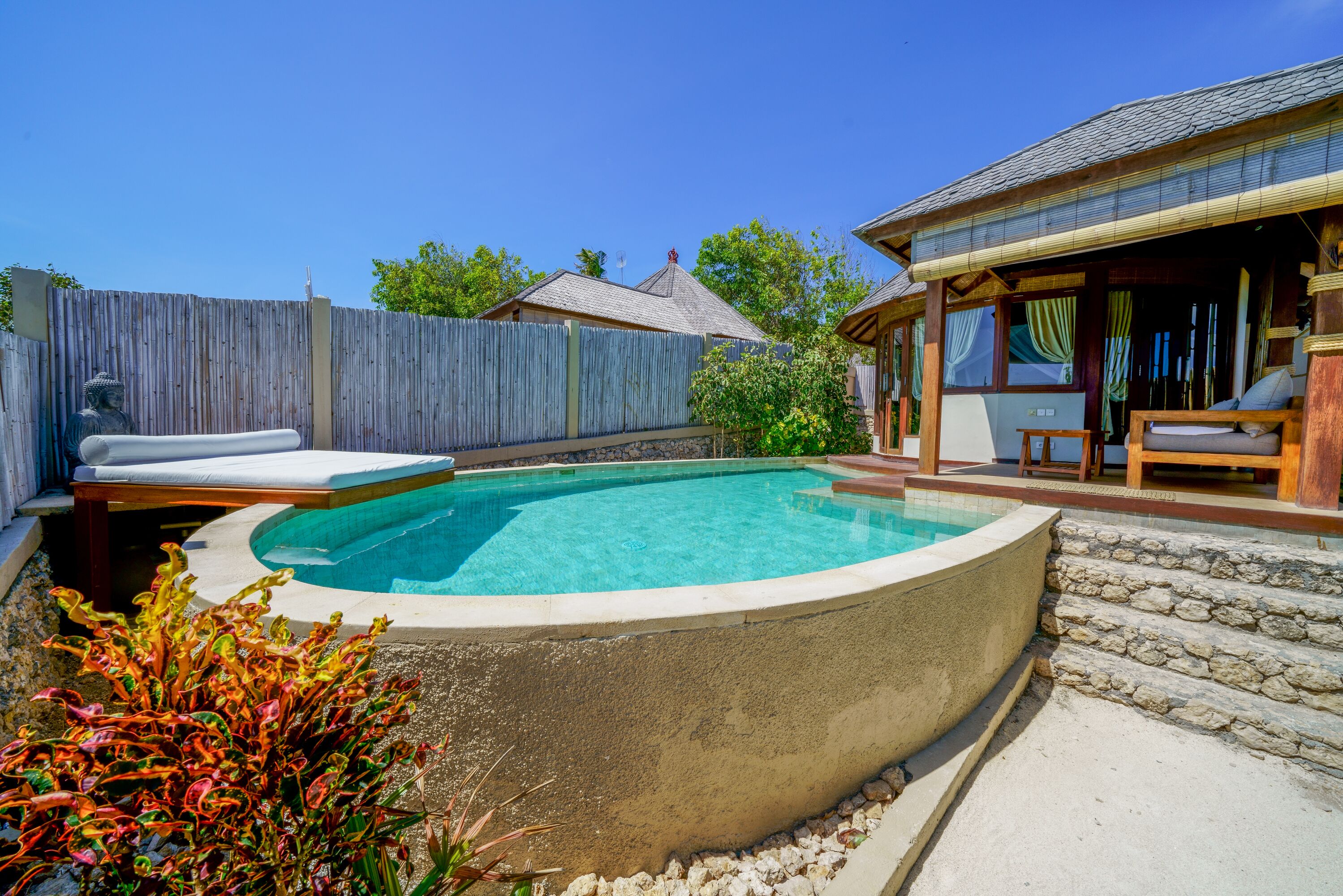 A swimming pool with a wooden deck, a covered seating area, and a stone wall.